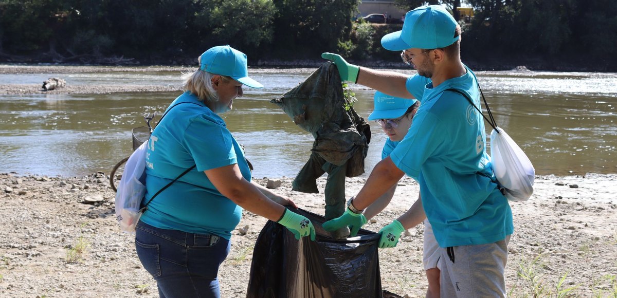 Colleagues collecting litter on a riverbank on World Environment Day