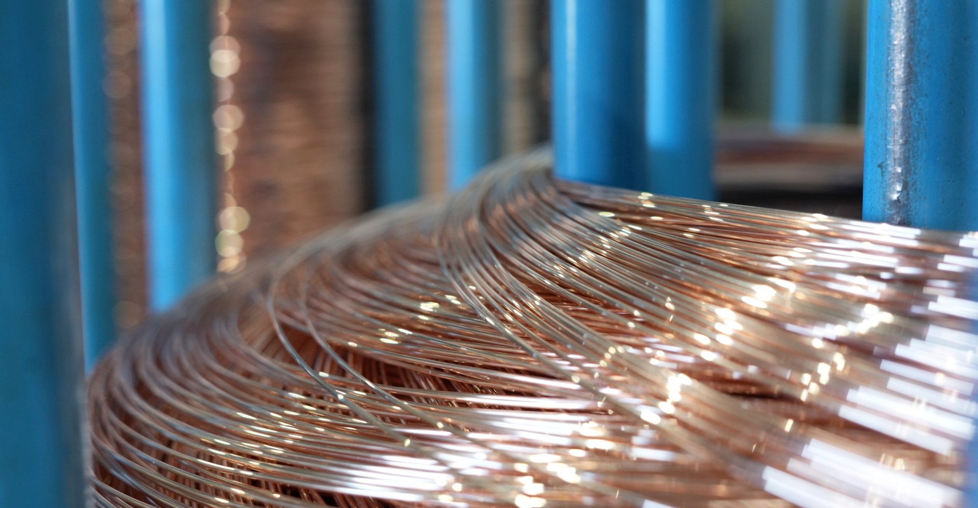 Close-up of copper wire coiled on a blue reel